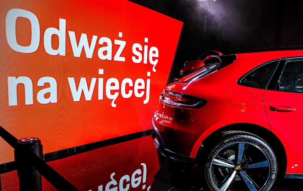 Czerwony samochód przy ekranie z hasłem Odważ się na więcej podczas premiery modelu