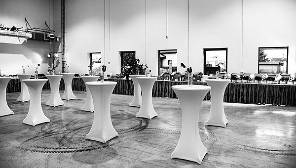 Hala magazynowa zaaranżowana na event, stoliki koktajlowe i bufet RAUT